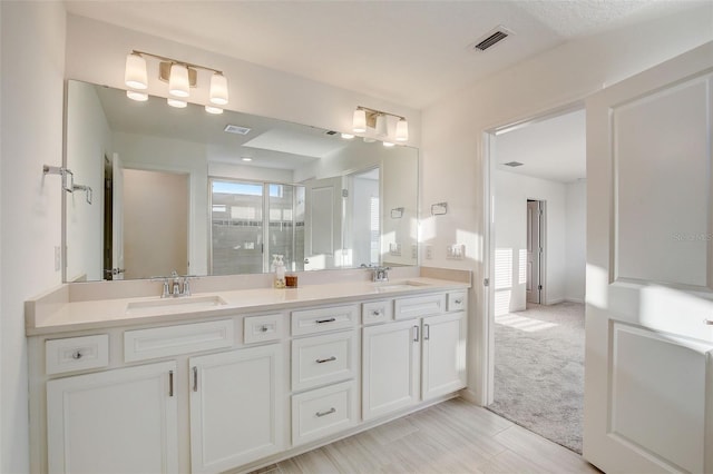 bathroom with double sink, tile flooring, a textured ceiling, and vanity with extensive cabinet space