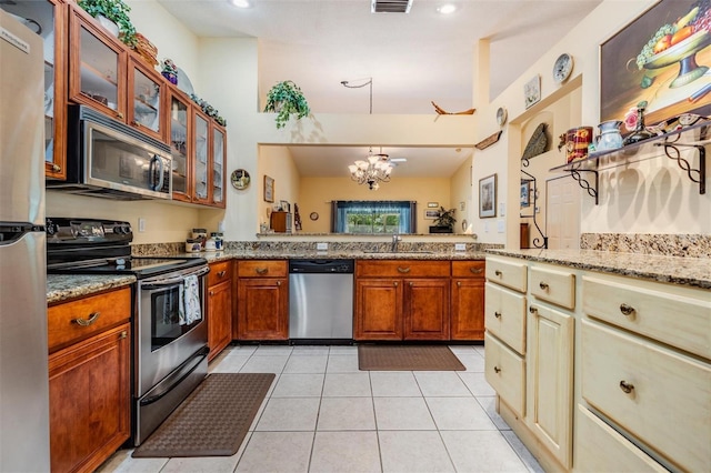 kitchen with sink, light tile floors, light stone counters, a chandelier, and stainless steel appliances