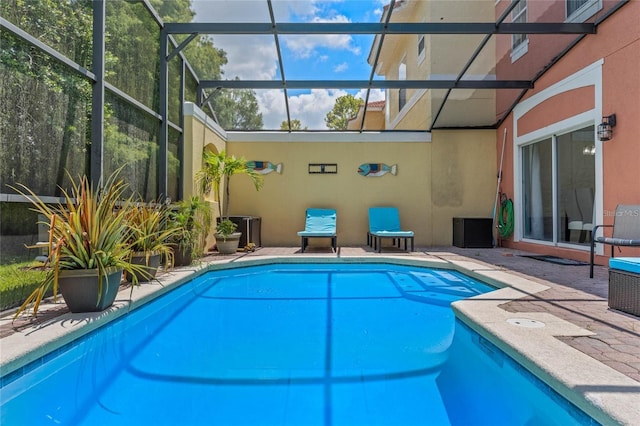 view of swimming pool featuring glass enclosure and a patio area