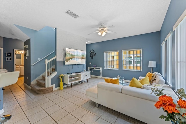 tiled living room with ceiling fan and a textured ceiling