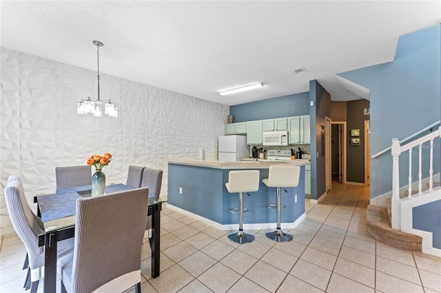 kitchen with a chandelier, light tile floors, white appliances, and a breakfast bar area