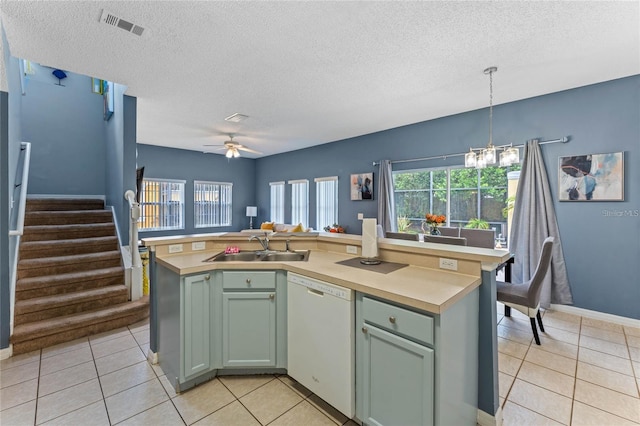 kitchen with pendant lighting, light tile floors, ceiling fan with notable chandelier, dishwasher, and sink