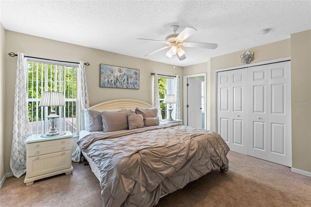 carpeted bedroom with a closet, a textured ceiling, multiple windows, and ceiling fan