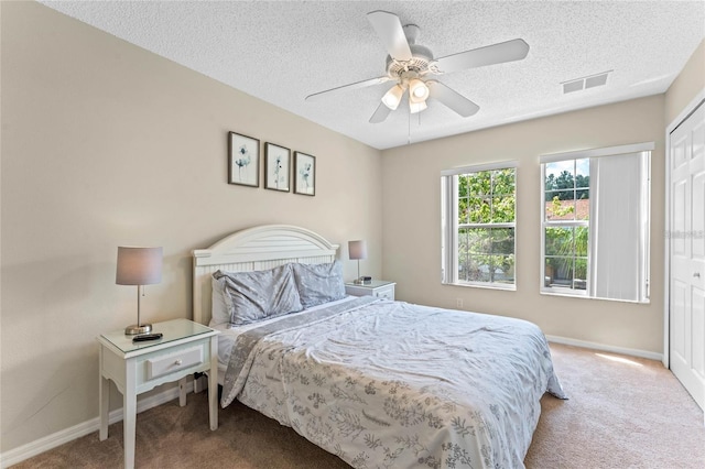 bedroom featuring a closet, carpet floors, a textured ceiling, and ceiling fan