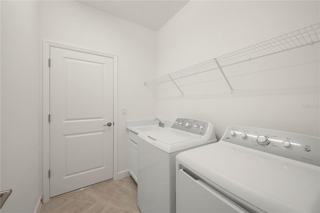 laundry area with cabinets, washer and dryer, light tile floors, and sink