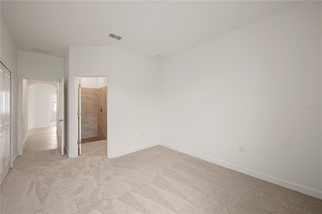 unfurnished bedroom featuring light carpet and connected bathroom