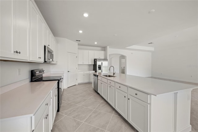 kitchen with an island with sink, stainless steel appliances, and white cabinets