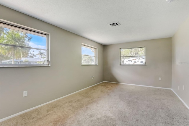 carpeted empty room with a textured ceiling