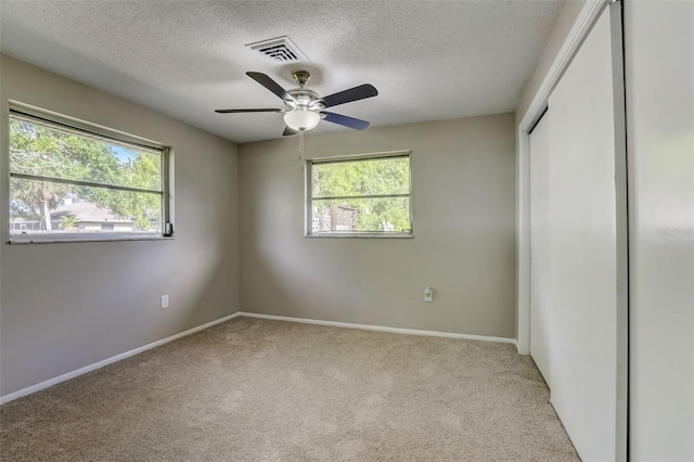 carpeted empty room with plenty of natural light, a textured ceiling, and ceiling fan