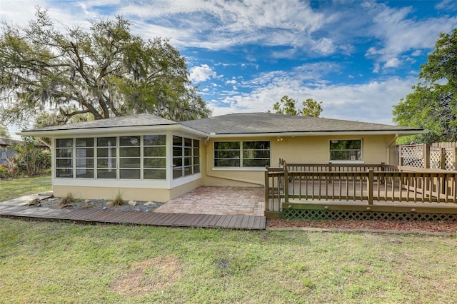 back of property featuring a lawn, a sunroom, and a wooden deck