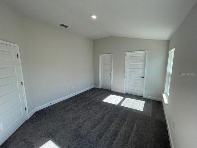 unfurnished bedroom with lofted ceiling and dark colored carpet