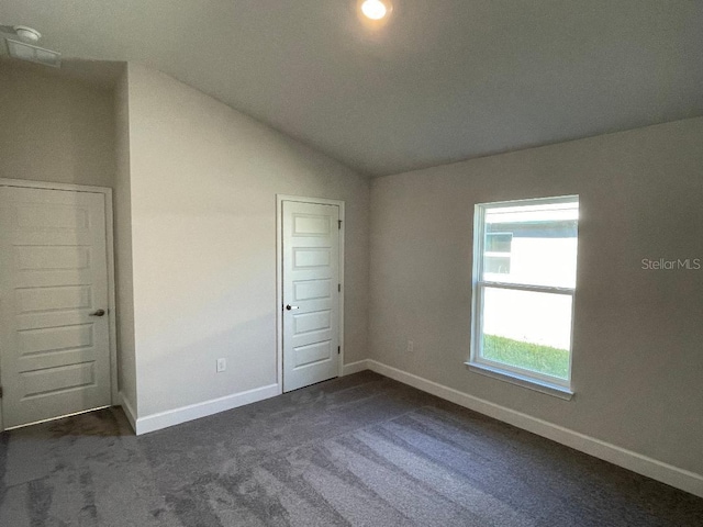 unfurnished bedroom with dark colored carpet, lofted ceiling, and a closet