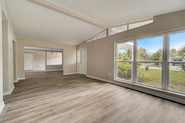 unfurnished living room with wood-type flooring and lofted ceiling with beams