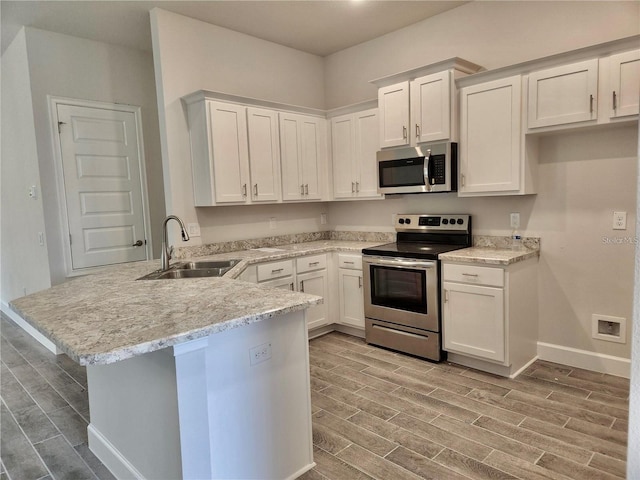 kitchen featuring kitchen peninsula, sink, light stone counters, white cabinets, and appliances with stainless steel finishes