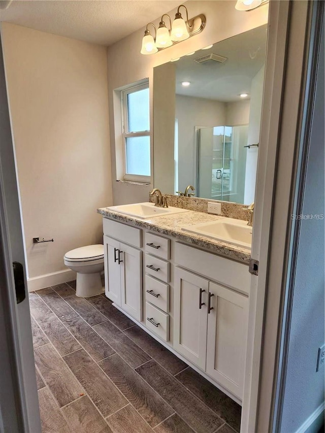 bathroom featuring toilet, double vanity, hardwood / wood-style floors, and a textured ceiling