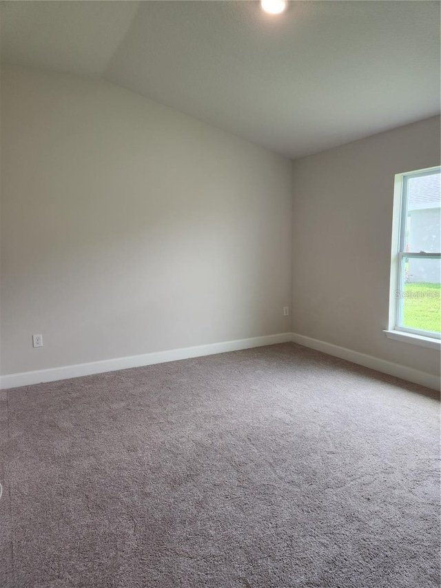 unfurnished room with carpet flooring and vaulted ceiling