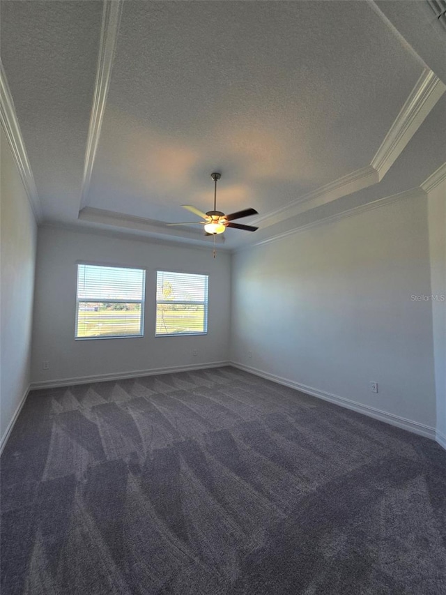 empty room featuring dark colored carpet, a tray ceiling, and ceiling fan