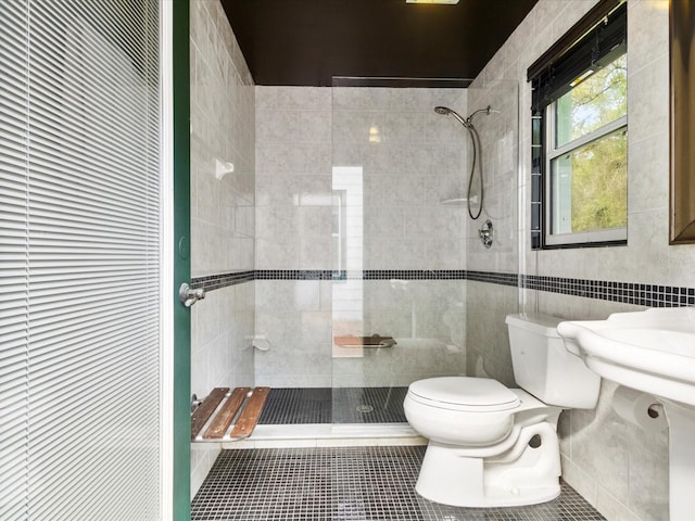 full bath with tiled shower, tile walls, toilet, and tile patterned floors