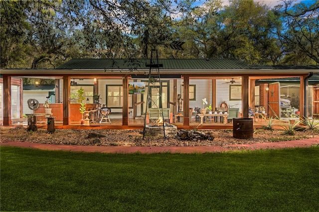 rear view of property with metal roof and a yard