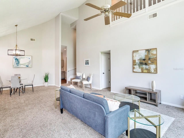 living room featuring light carpet, high vaulted ceiling, and ceiling fan with notable chandelier