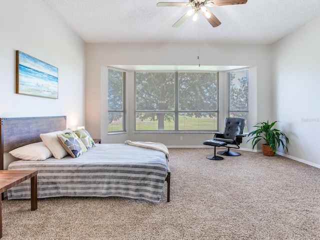 bedroom featuring a textured ceiling, multiple windows, ceiling fan, and light colored carpet