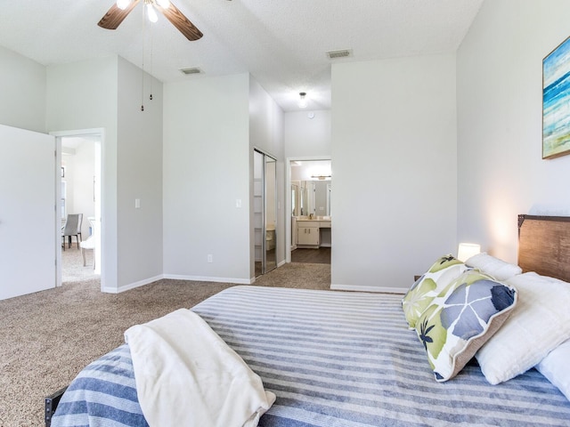 bedroom featuring ceiling fan, dark carpet, a high ceiling, ensuite bath, and a textured ceiling