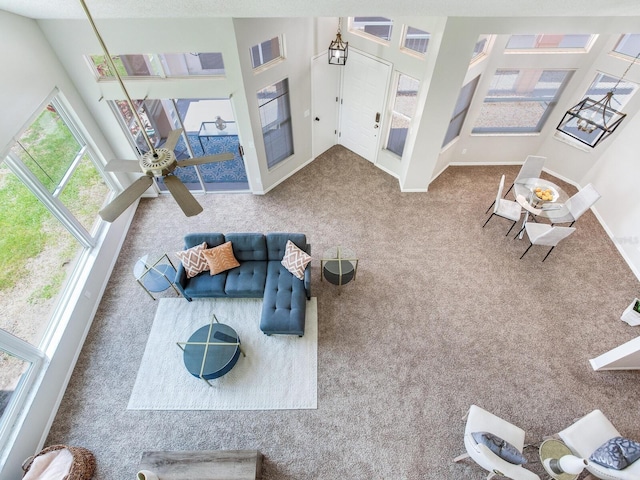 living room with light carpet, ceiling fan, and a towering ceiling