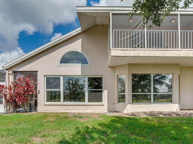 back of house featuring a balcony and a lawn