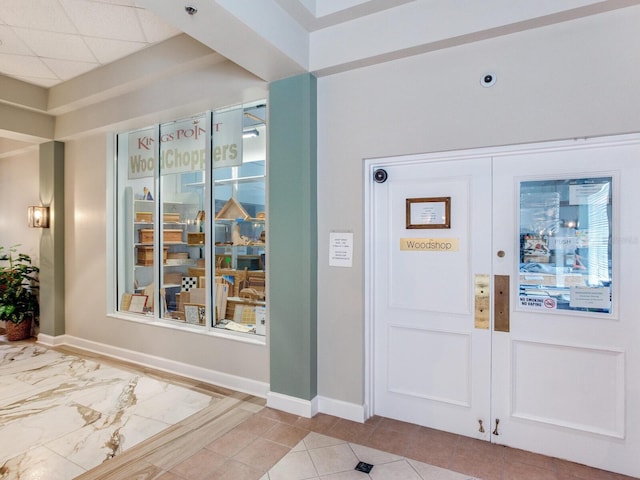 tiled foyer entrance featuring a paneled ceiling and french doors