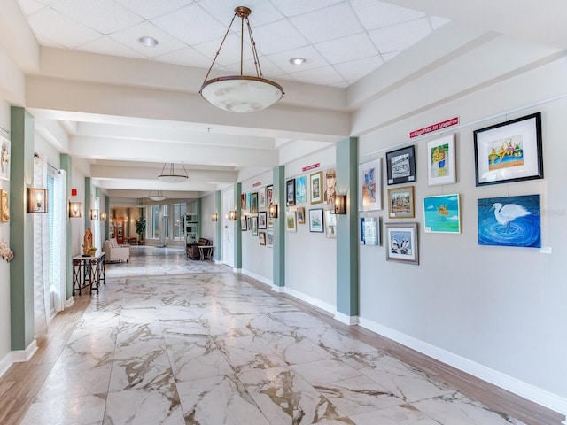 hallway with light tile floors and a paneled ceiling