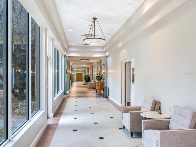 hall featuring a chandelier, a raised ceiling, and light wood-type flooring