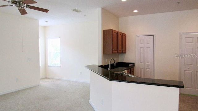 kitchen featuring light colored carpet, ceiling fan, and sink