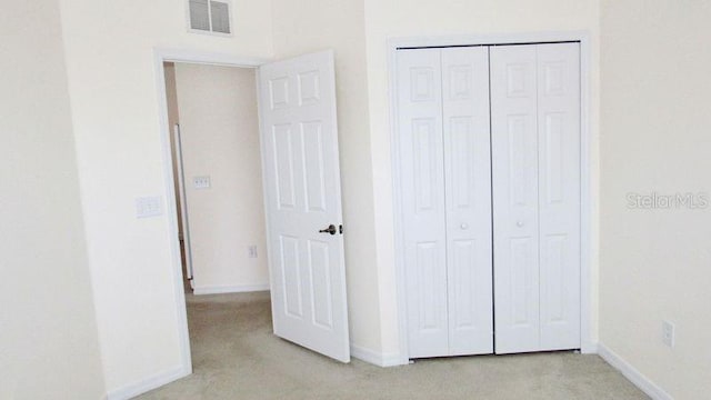 unfurnished bedroom with light carpet and a closet