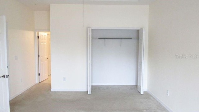 unfurnished bedroom with a closet and light colored carpet