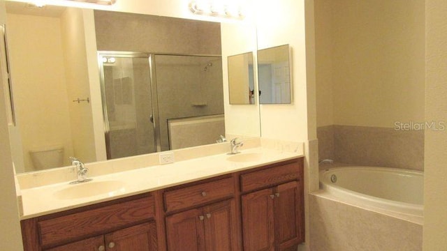 full bathroom featuring dual sinks, toilet, separate shower and tub, and vanity with extensive cabinet space