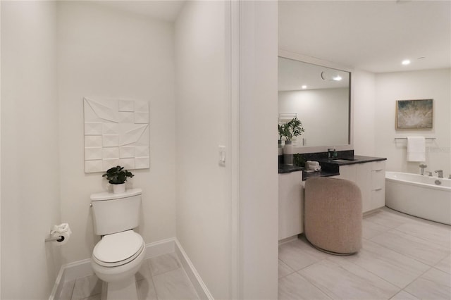 bathroom with tile patterned floors, a tub, vanity, and toilet