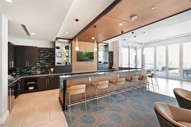 interior space with a kitchen breakfast bar, a center island, dark brown cabinets, tasteful backsplash, and hanging light fixtures