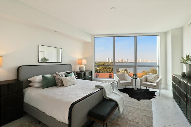 bedroom featuring light tile patterned flooring, floor to ceiling windows, and a water view