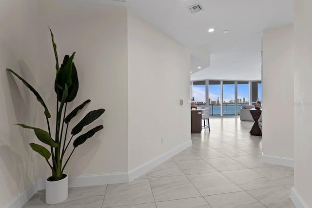 corridor with floor to ceiling windows and light tile patterned floors