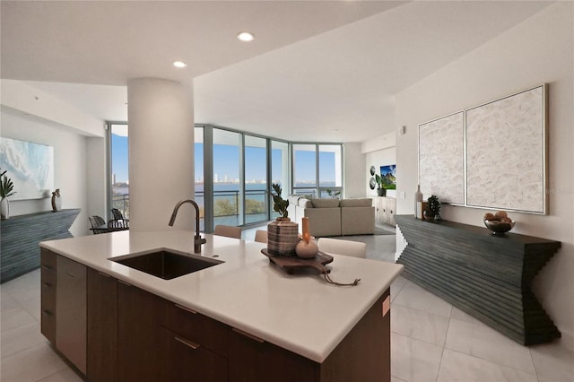 kitchen with a kitchen island with sink, sink, a wall of windows, and a water view