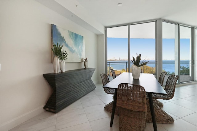 dining room with floor to ceiling windows, a water view, and light tile patterned floors