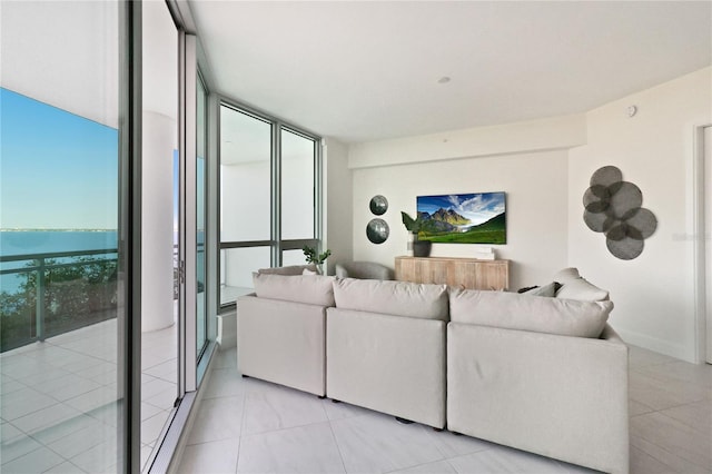 tiled living room featuring floor to ceiling windows and a water view