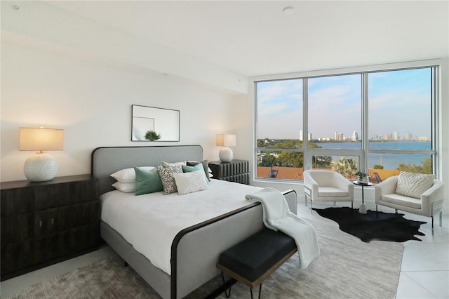 tiled bedroom featuring a wall of windows and a water view