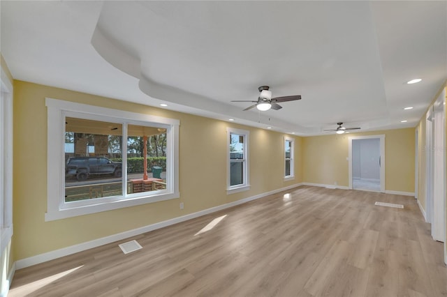 unfurnished room featuring a tray ceiling, ceiling fan, and light hardwood / wood-style flooring