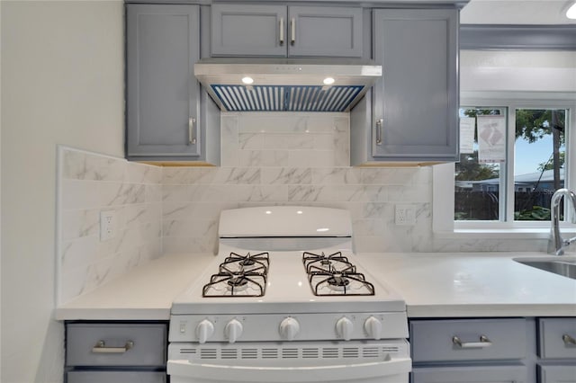 kitchen with white range oven, gray cabinetry, sink, and wall chimney range hood