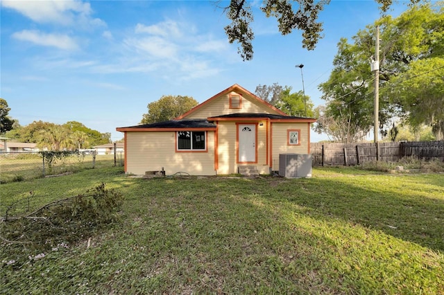 rear view of property featuring a yard and central AC