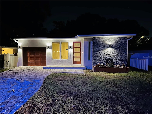 view of front of home with covered porch, a lawn, and a garage