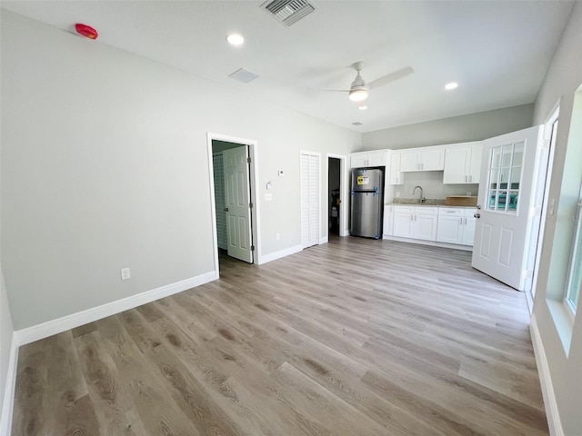 unfurnished living room with ceiling fan, sink, and light wood-type flooring