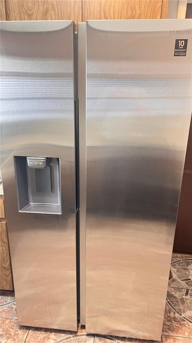 interior details featuring light tile flooring and stainless steel fridge