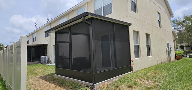 view of side of home featuring a yard, a sunroom, and central AC unit